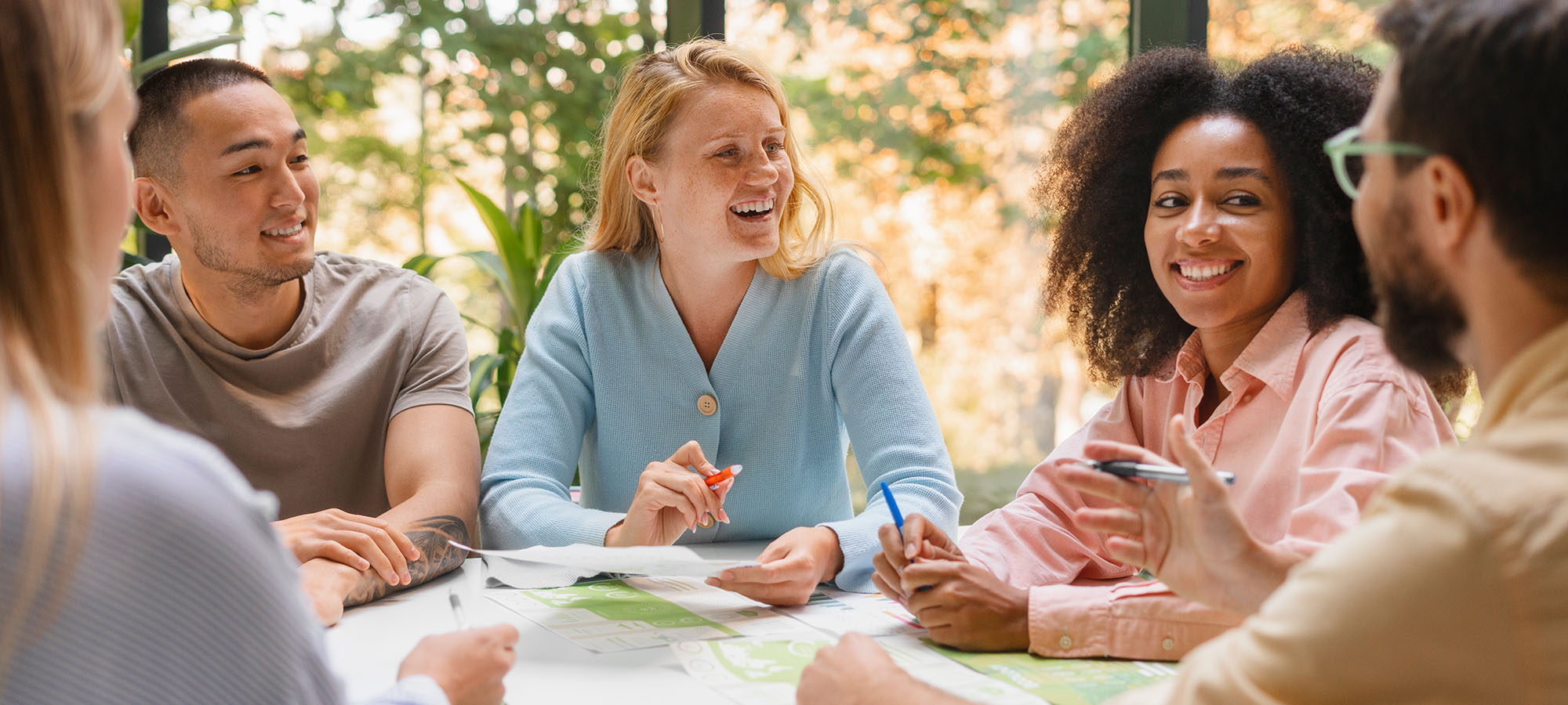 Cinq personnes autour d'une table ronde avec des papiers et des stylos