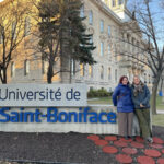 Deux femmes devant l'enseigne de l'Université Saint-Boniface.