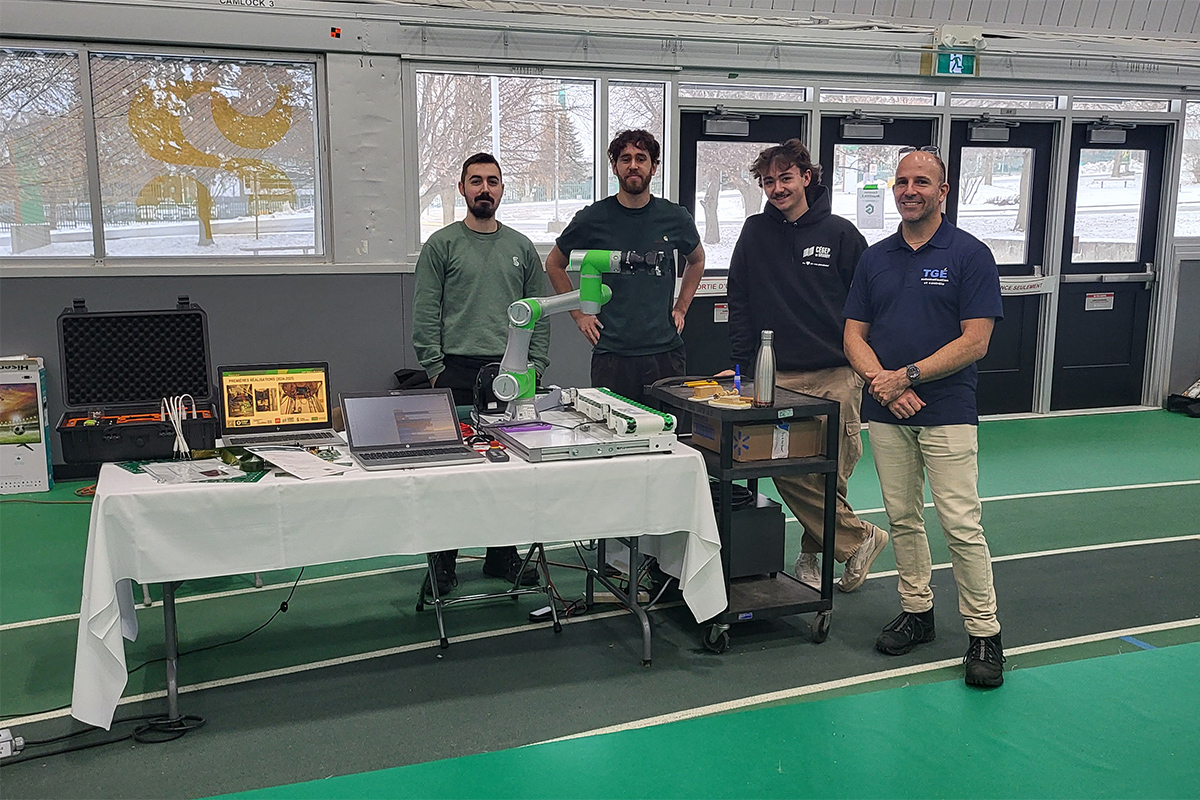 Quatre hommes debout à côté d'une table d'exposition technologique