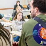 En avant plan, vue de dos d'une femme et d'un homme qui joue de la guitard