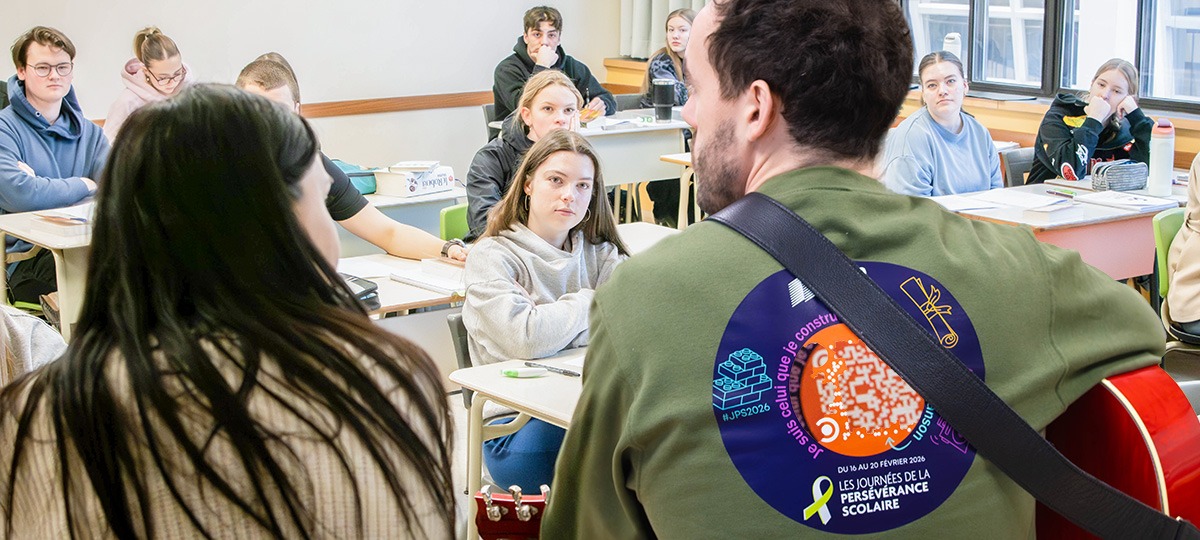 En avant plan, vue de dos d'une femme et d'un homme qui joue de la guitard
