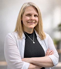 Une femme blonde souriante avec les bras croisés