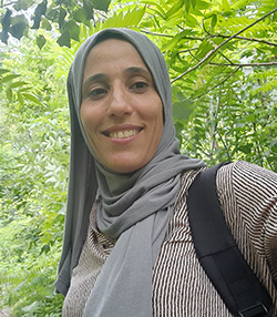 Une femme musulamne souriante devant des arbres