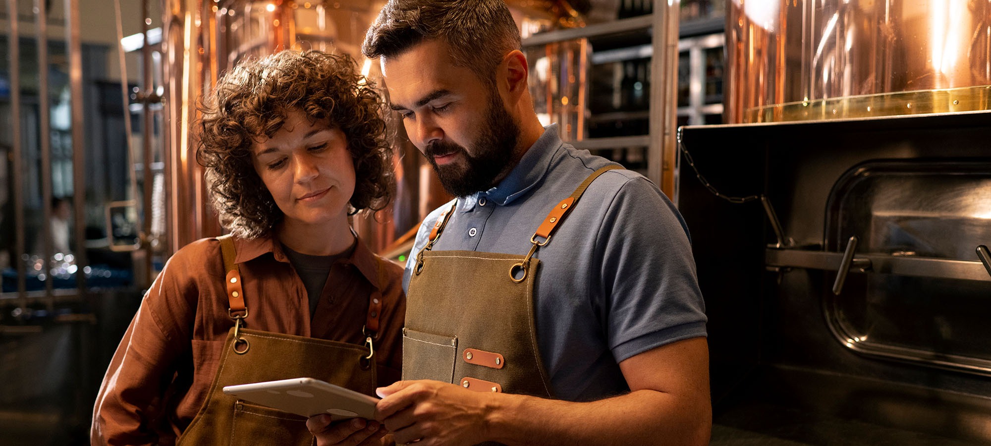 Dans un restaurant, une femme et un homme regardent l'écran d'une tablette