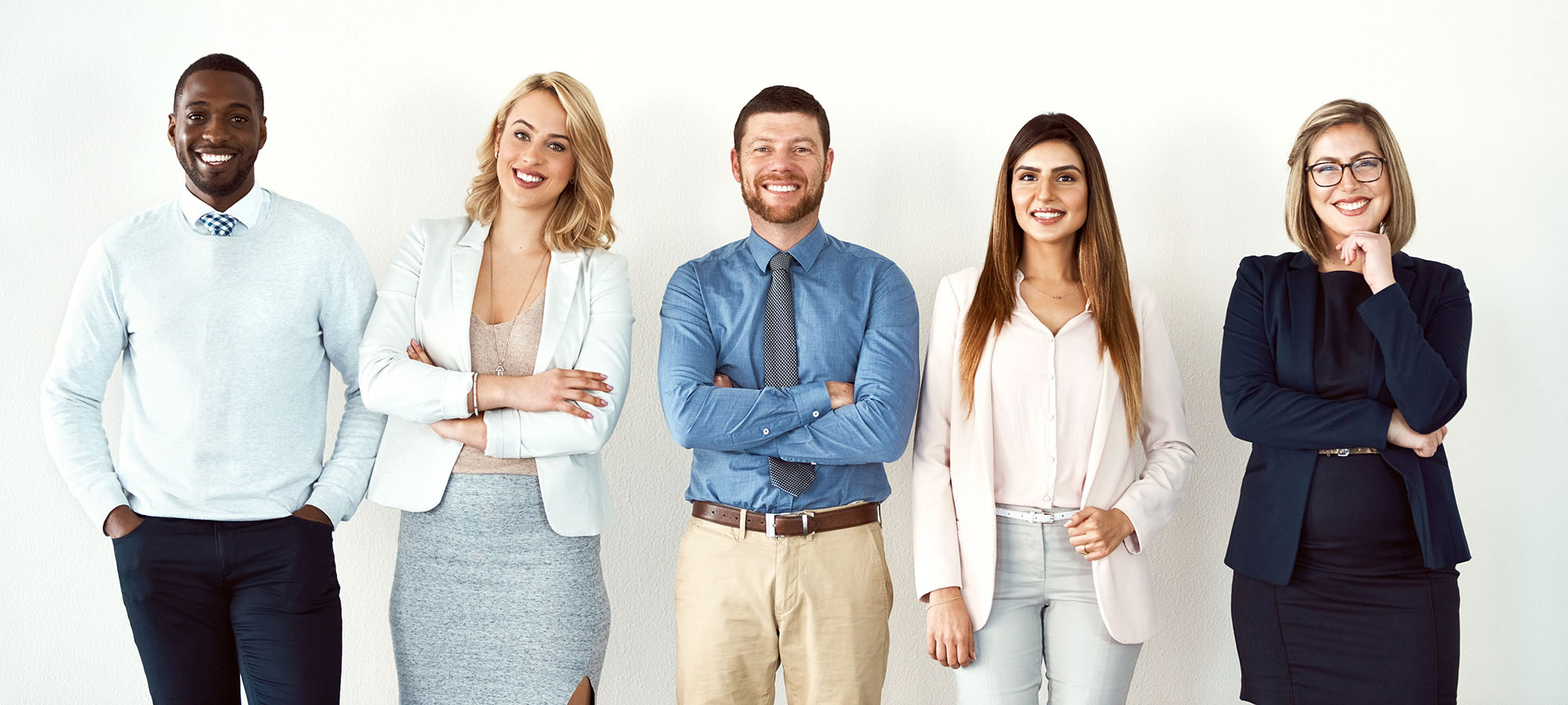 Cinq personnes debout qui affichent un grand sourire