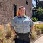 Une agente de sécurité souriante debout devant le mur extérieur d'un bâtiment