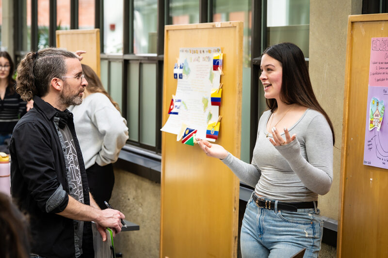 Une étudiante à un kiosque explique quelque chose à un enseignant
