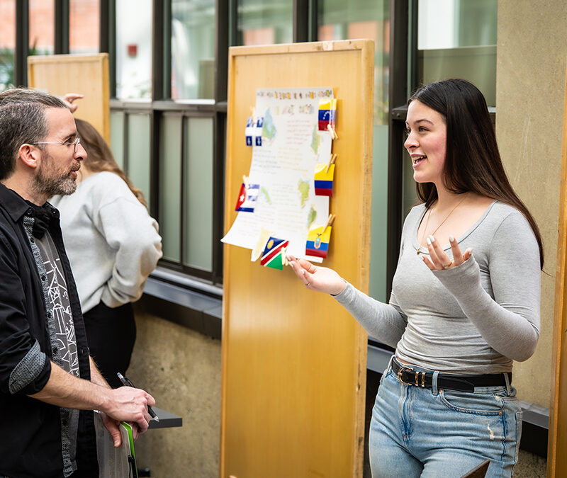 Une étudiante à un kiosque explique quelque chose à un enseignant