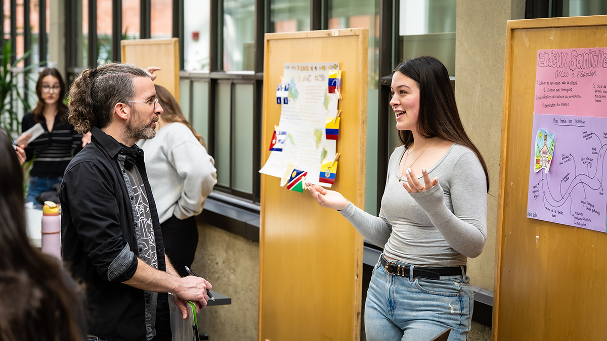 Une étudiante à un kiosque explique quelque chose à un enseignant