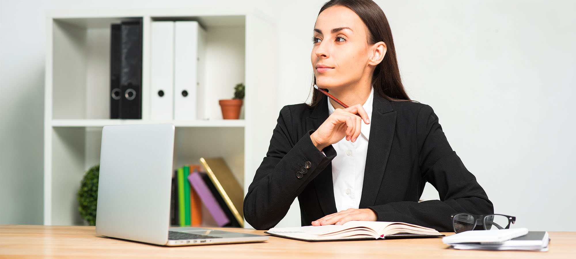 Dans un bureau, une femme assise à une table tient un crayon