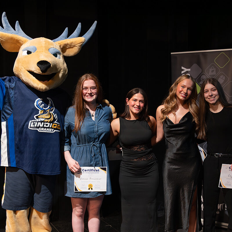 Remise de prix avec une mascotte de cerf et 4 jeunes femmes sur la scène