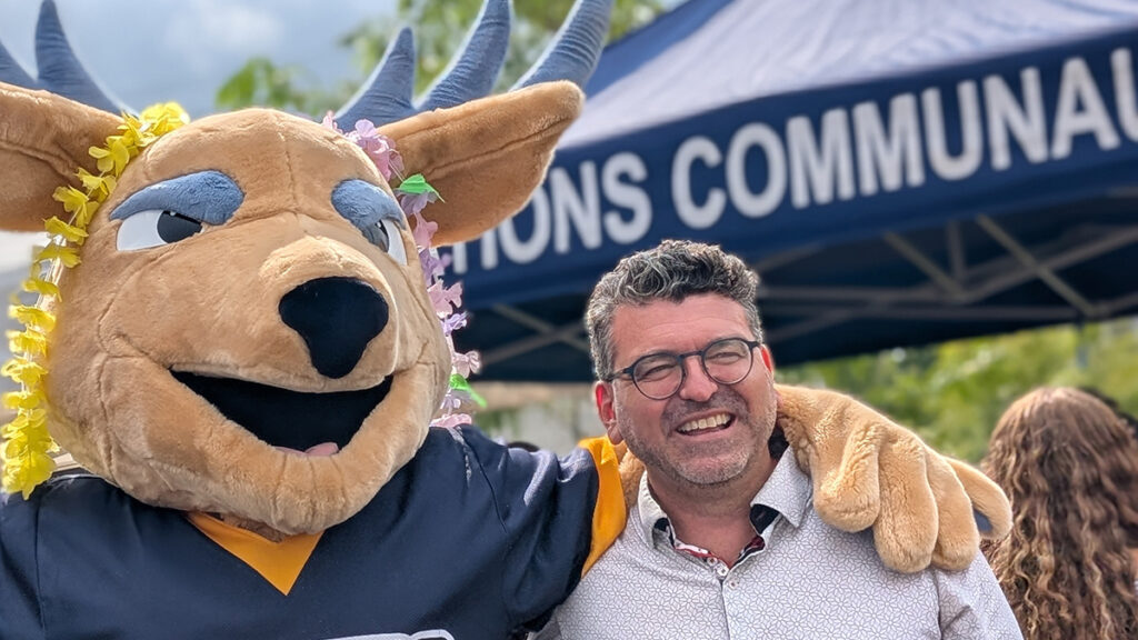 Mascotte à tête de chevreuil et un homme souriant