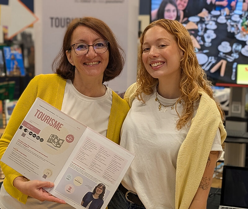 Une femme et une jeune fille à un kiosque d'informaton où est écrit : Tourisme