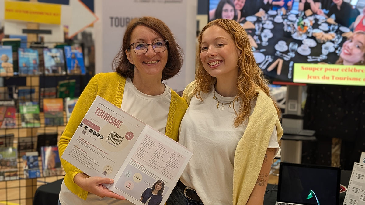 Une femme et une jeune fille à un kiosque d'informaton où est écrit : Tourisme